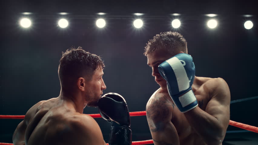 Cinematic Super Slow Motion Sports Footage with Two Professional Boxers Fighting in a Ring. Male Athlete Punching the Opponent in the Face. Sweat Spraying Everywhere From the Heavy Impact Royalty-Free Stock Footage #1110270027