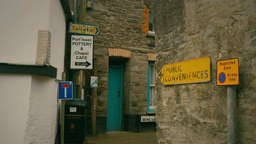 Narrow Lane in fishing village, Port Issac, with old Georgian cottages built closely together. pathway winds up hill. Old signage in forground