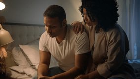 African American sad man sit on bed night evening at home suffer worried breakdown regret erectile dysfunction loving woman wife hug comforting support empathy crisis impotence potency health problem - Powered by Shutterstock - Get 15% off with code: PIKWIZARD15