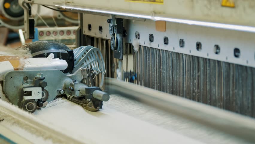 weaving looms. weaving factory. textile industry. Close-up. Automated weaving machine is fabricating cloth of threads. Textile factory equipment. fabric production.