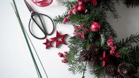 Festive video of Christmas wreath making with your own hands. Decor and decoration for the house, fir branches, stars,cones, wire and scissors lying on the table, view from above.Christmas floristics.