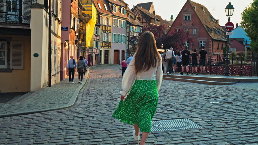 Beautiful Girl walking in La Petite Venise in Colmar's colourful timbered houses. A female tourist enjoying Colmar town in Grand Est France with cobblestone streets Royalty-Free Stock Footage #1110276057