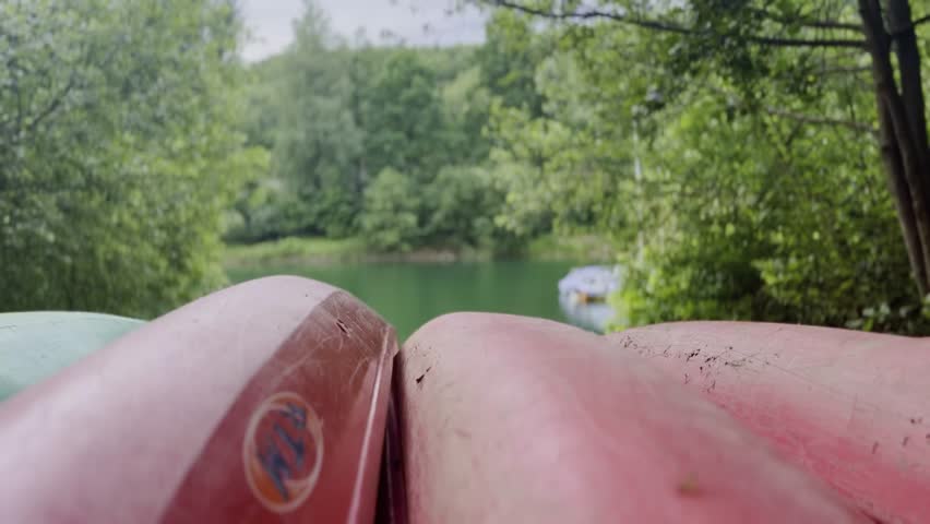 Red boats canoes lie upside down on the shore of a lake