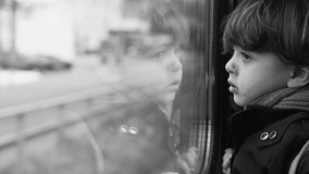 Monochromatic pensive child staring at landscape pass by from high-speed train transportation, black and white clip of thoughtful kid traveler
