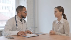 Young Doctor Talking with Old Patient in Clinic