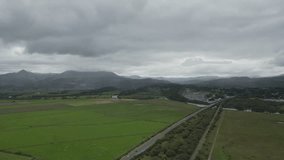 Drone video shot of patched green valley with a car road in Wales.