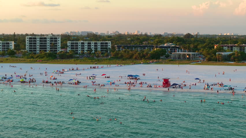 Aerial evening seascape with Siesta Key sandy beach in Sarasota, USA. Many tourists enjoying summer vacation time swimming in warm Mexico gulf water and sunbathing on hot Florida sun