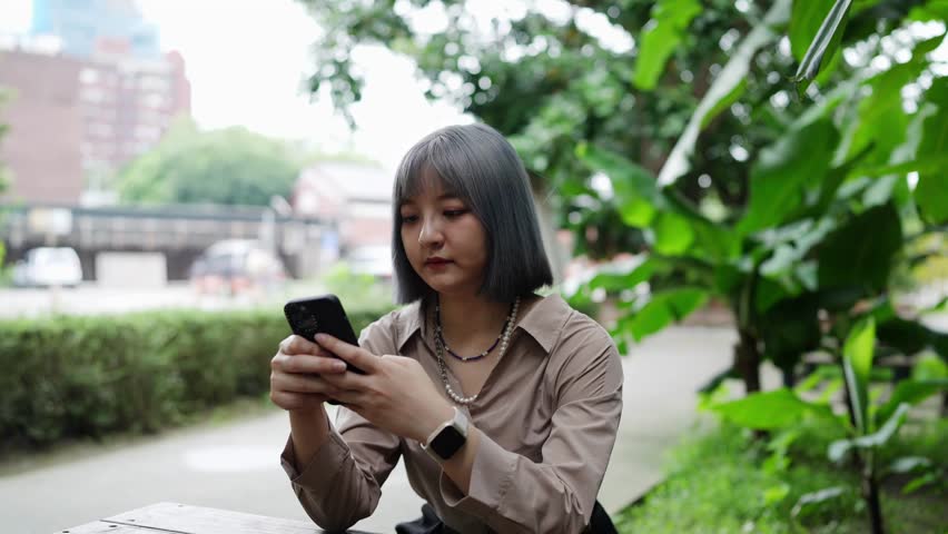 A young Taiwanese woman sits and operates her smartphone in an artistic building in the Huashan 1914 Cultural and Creative Park in Taipei.