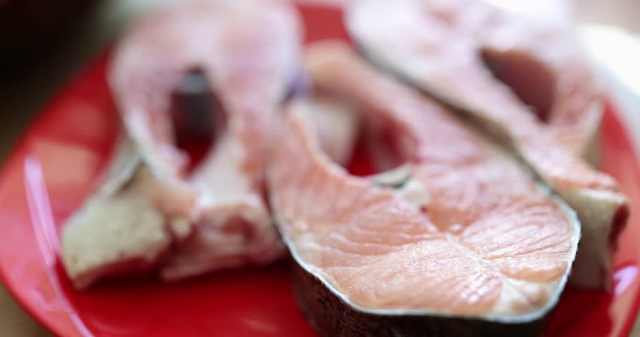 Fresh salmon steaks on a pink plate, shallow focus, close-up. Concept healthy food, raw pieces of fish