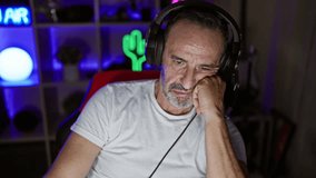 Middle-aged man, grey hair and bored face, streaming games in a dark room, life of an adult gamer