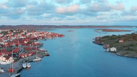 Between the islands in archipelago at sunset evening. Fishing town by the shore in Sweden. Aerial drone flight over ocean channel protected bay