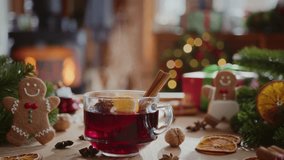 cozy composition of hot steaming mulled wine with orange slice, cinnamon stick and anise in glass mug. christmas decorations, gingerbread cookies, fir branches and flame in fireplace on background - Powered by Shutterstock - Get 15% off with code: PIKWIZARD15