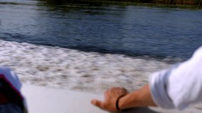 A man's hand rests on the side of a speedboat yacht. sailing fast on the water leaving waves and foam. A trip on a motorboat on the river. Rest of rich people. A gentleman in a white shirt traveling