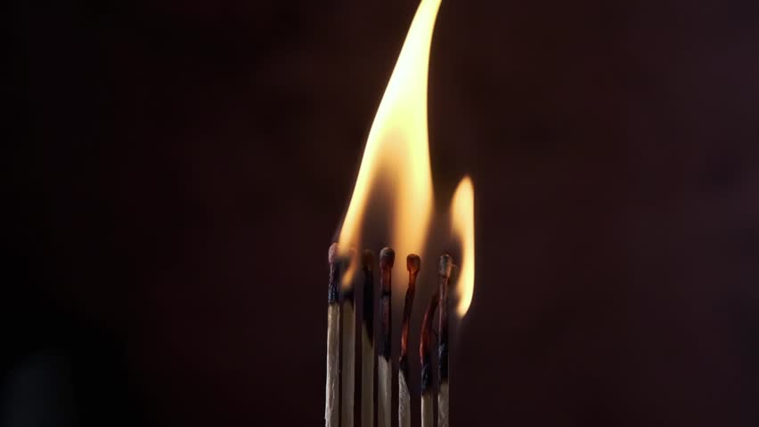 a row of matches are lit on a dark background