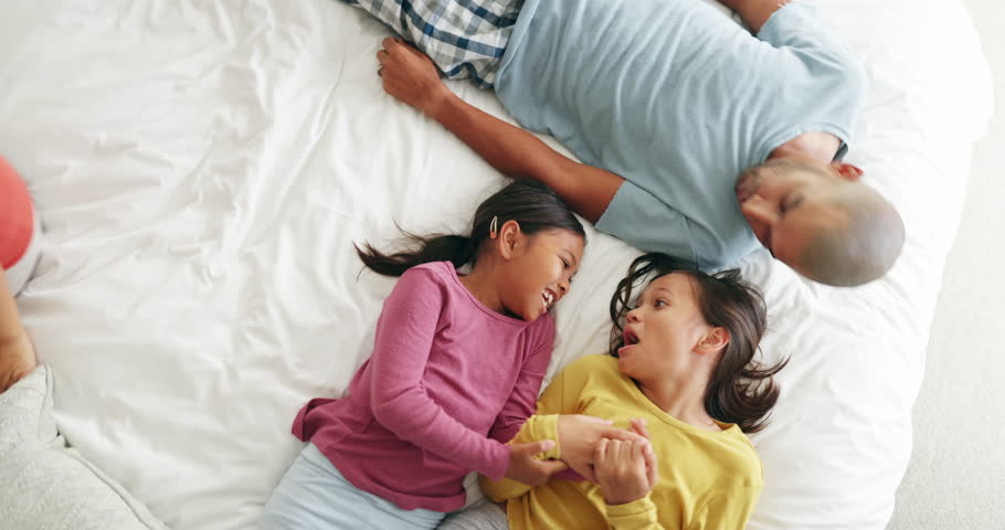 Bedroom, top view and happy family love, relax and enjoy quality time together for care, comfort and bonding. Home fun, smile and happy mother, father and young excited children lying on mattress bed Royalty-Free Stock Footage #1110319419