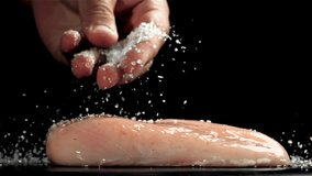 A man sprinkles salt on chicken meat. Filmed on a high-speed camera at 1000 fps. High quality FullHD footage