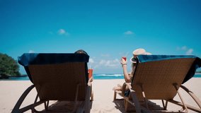 Man and woman lie on sun lounger and drink cocktail on sandy beach near ocean. Couple relaxing on sun lounger and drinking cocktail beach in the sunshine.Couple on tropical beach.Holidays and travel - Powered by Shutterstock - Get 15% off with code: PIKWIZARD15