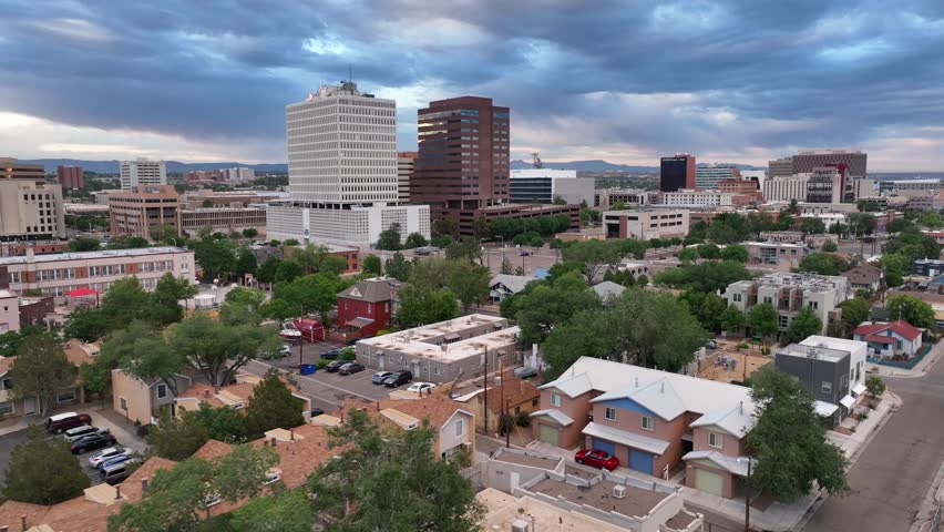 Albuquerque establishing shot. Aerial flight above downtown city in New Mexico. Urban skyscrapers and houses during golden hour light.