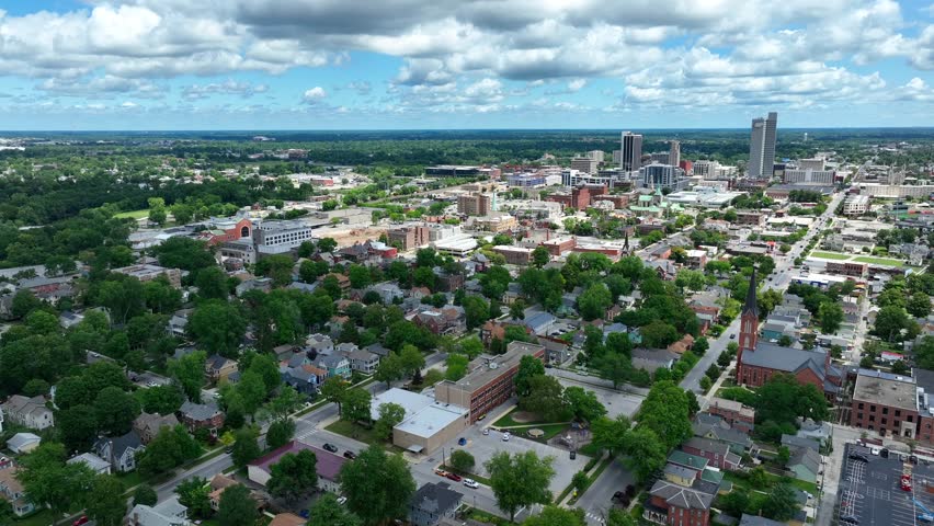 Sprawling landscape of Fort Wayne, Indiana on beautiful summer day. Aerial shot of city skyline and neighborhood with green trees.
