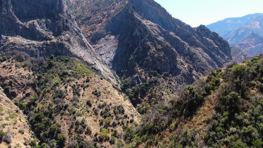 Aerial shot over Kings Canyon majestic hills, verdant trees, and the Kings River in the backdrop, bathed in California