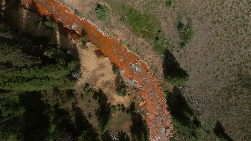 Aerial cinematic drone orange river Cement Creek summer high altitude Silverton Ski Area resort Telluride Prospect Gulch Colorado Rocky Mountains stunning drive looking down movement