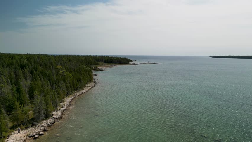 Aerial ascent up forested coastline, Lake Huron, Michigan