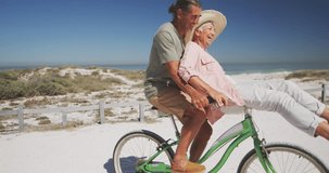 Animation of social media text and icons over caucasian couple riding bike on beach. Global social media, digital interface, computing and data processing concept digitally generated video.