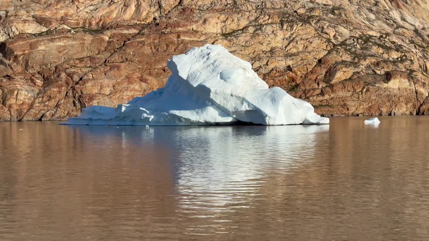 Small iceberg drifting by inbeautiful morning light in Ø Fjord, Scoresbysund, Greenland.