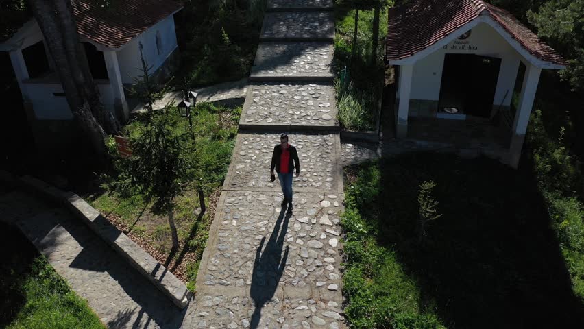 Man walking between chapes on a path di cruciferous forest. Holy place where a piece of Jesus Christ cross is buried in Rhodope mountain, Bulgaria. Amazing Green Hills in Plovdiv region. Royalty-Free Stock Footage #1110339091