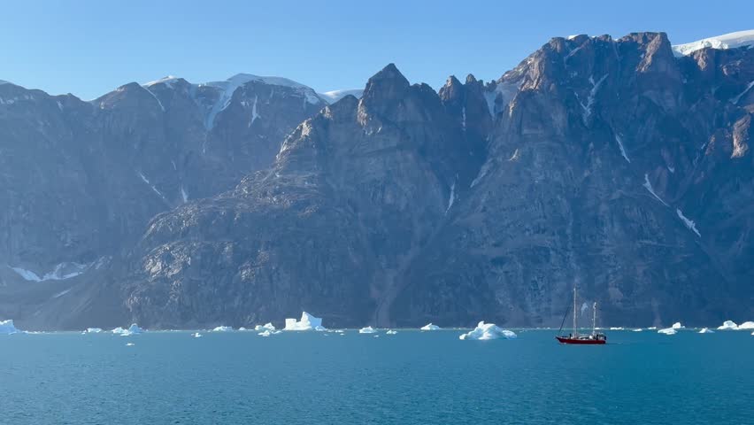 A two-masted yacht between icebergs in Ø Fjord. Scoresbysund, Greenland.