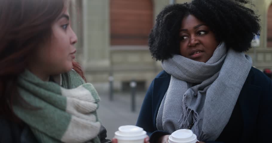 Multiracial women with take away coffee cup meeting and talking together in the city during winter time  Royalty-Free Stock Footage #1110340717