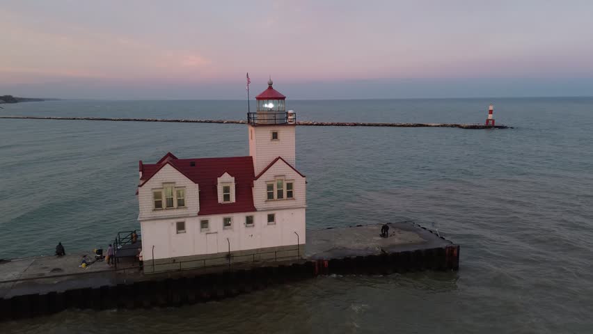 Kewaunee lighthouse on Lake Michigan. Rotating aerial shot around the lighthouse, at light room level, shows the beacon, ship channel and piers. Shot at dusk.