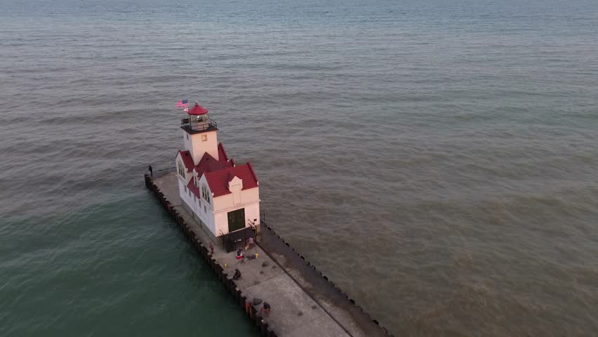 Kewaunee lighthouse on Lake Michigan. High angle aerial flyover shot of the lighthouse and the end of the pier. Shot shows calm water on one side and choppy water on the other. Shot at dusk.