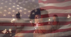 Composite video of usa flag over happy african american woman celebrating with sparkler at beach. Partriotism and independence day celebration concept