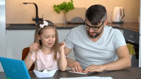 Father and child build origami paper boats use video tutorial on tablet at home. Happy family learning handmade crafts. Leisure, diy