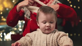 Mom put on sweet little funny baby boy red Santa hat at background of decorated fir-tree celebrate Christmas together. Happy family at holidays home. Curious child portrait. Merry Christmas, new year - Powered by Shutterstock - Get 15% off with code: PIKWIZARD15