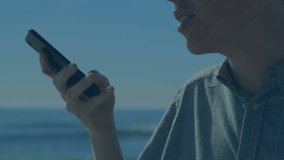 Animation of stock market data processing against asian man talking on smartphone near the sea. Global economy and business data technology concept - Powered by Shutterstock - Get 15% off with code: PIKWIZARD15