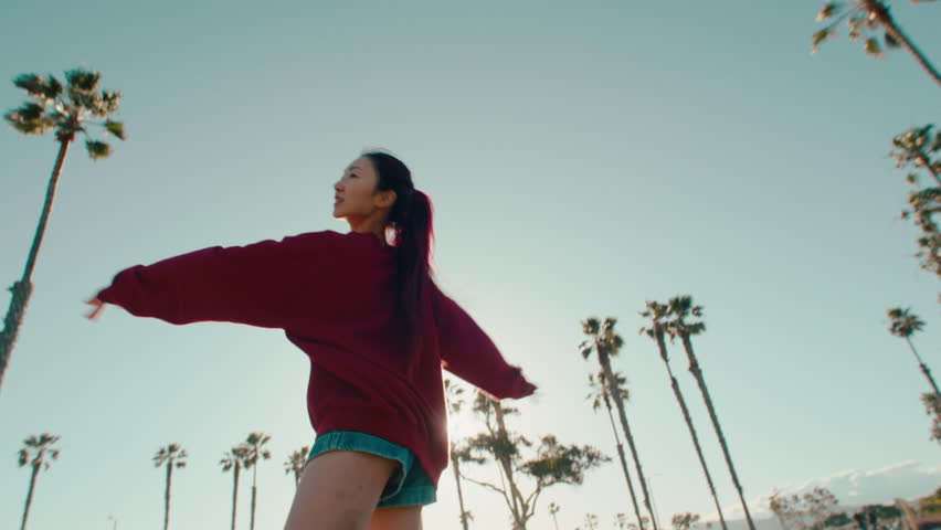 Asian girl longboarding in a park