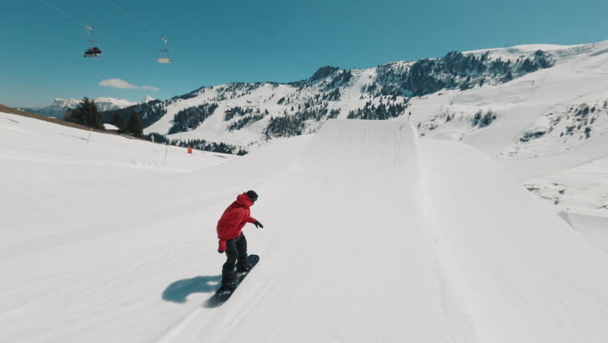 FPV drone shot of a snowboarder on a ramp doing a flip on a sunny day