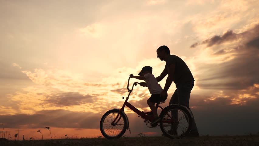happy family in the park. father teaching son to ride a bike at sunset silhouette in the park. son child learning to ride a bike at sunset father helping son. child playing lifestyle riding bike Royalty-Free Stock Footage #1110357245