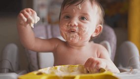baby eats dirty. happy family kid toddler concept. lifestyle baby girl dirty sitting messing with food at the table for feeding in the kitchen. grimy toddler in the kitchen - Powered by Shutterstock - Get 15% off with code: PIKWIZARD15