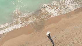 video from a drone of the Bride and Groom hugging each other on the sand of the Mediterranean coast near the azure sea waves and the glare of the sun.Drone video of two people in love against the sea - Powered by Shutterstock - Get 15% off with code: PIKWIZARD15