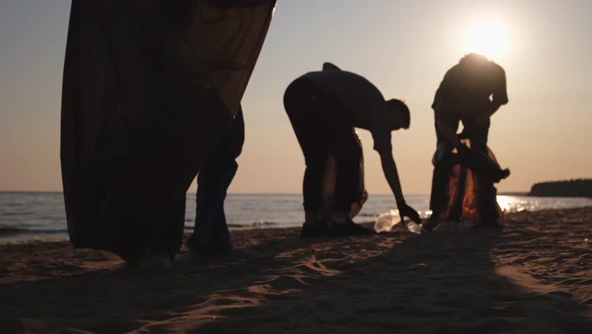 Earth day. Volunteers activists collects garbage cleaning of beach coastal zone. Woman and mans puts plastic trash in garbage bag on ocean shore. Environmental conservation coastal zone cleaning Royalty-Free Stock Footage #1110359547