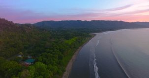 Stunning colorful sunset over an empty beach in Ballena Bay Costa Rica on a calm summer night as small rolling waves approach the sandy tropical beach