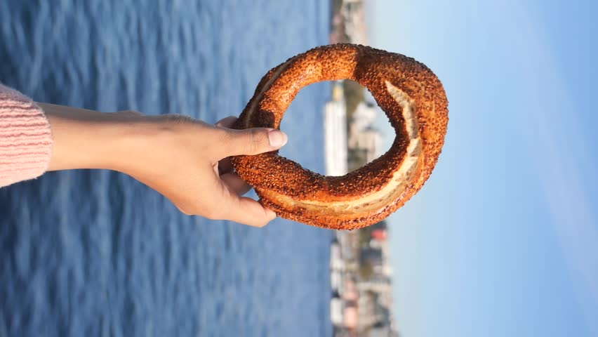 women holding a Turkish Bagel Simit against istanbul city background 