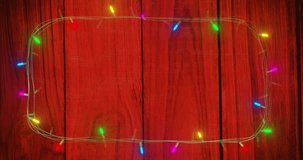 Animation of happy new year text and fairy lights on wooden background. New year, christmas, tradition and celebration concept digitally generated video.