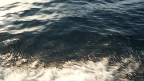 splashes of sea water with white foam from the movement of a boat on dark azure sea water, close-up top view, material for video gluing, video transition, romantic review video of yachting