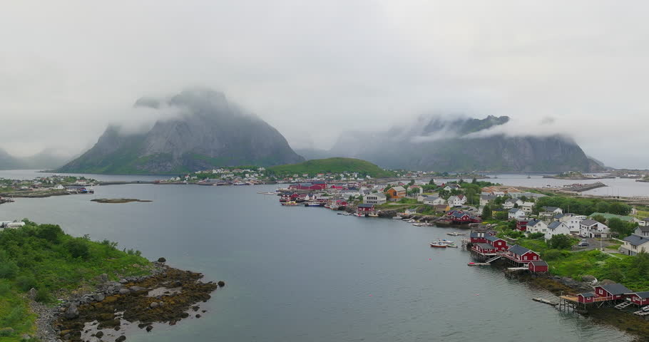 Traditional red fishermen houses of Reine Lofoten with foggy mountains, aerial