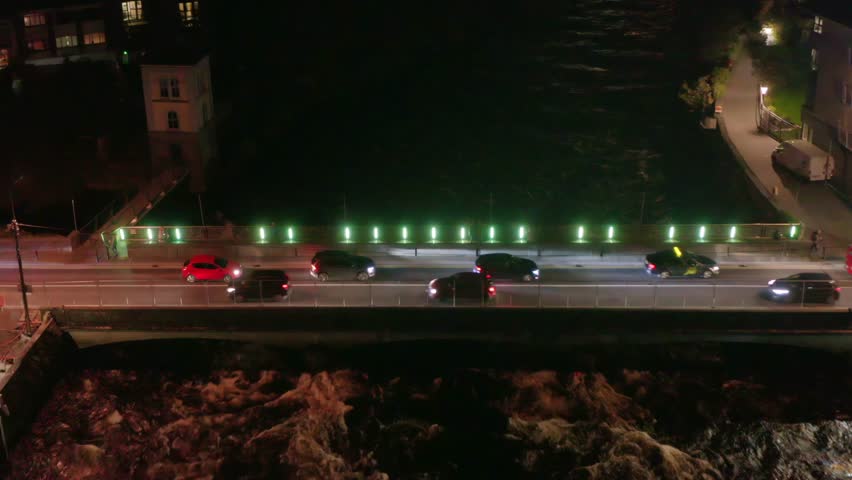 Bridge over a flowing river with traffic at nighttime. Slow motion