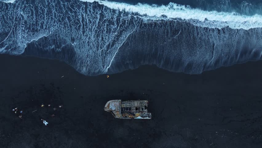 Aerial 4K Drone Footage: Tranquil Goa Lawa beach, Karangasem, Padangbai, East Bali; Ocean Waves hitting black sand beach - Top-Down shot; Ideal for Travel Blogs, Vlogs, and Documentaries